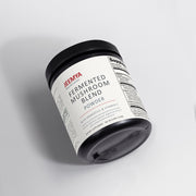 Angled view of the Jeemya Fermented Mushroom Blend Powder container on a minimalist white background, showcasing the product packaging.