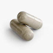 Close-up of two beige Max Detox capsules on a white background, highlighting the capsule size, smooth texture, and easy-to-swallow dietary supplement form.