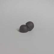 Close-up of two dark mushroom gummies on a white background, highlighting their rounded shape, smooth texture, and chewable dietary supplement form.