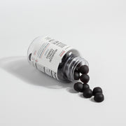 Jeemya Mushroom Extract Complex gummies bottle lying on its side with dark mushroom gummies spilling onto the surface, illustrating the gummy shape, texture, and product contents.